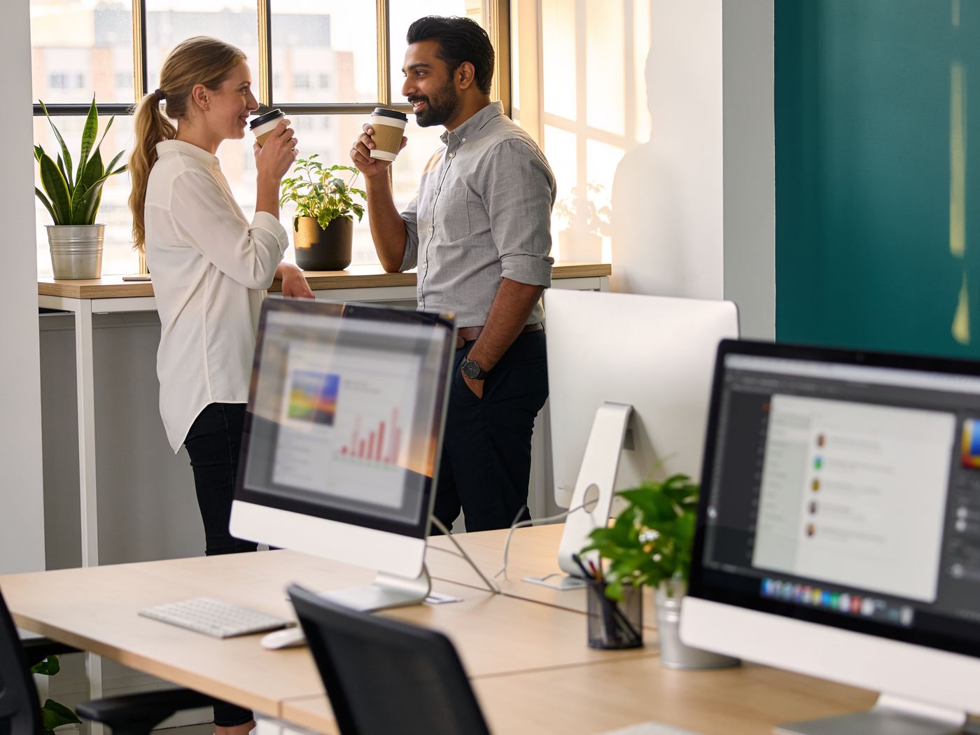 Two colleagues talking over coffee by the window