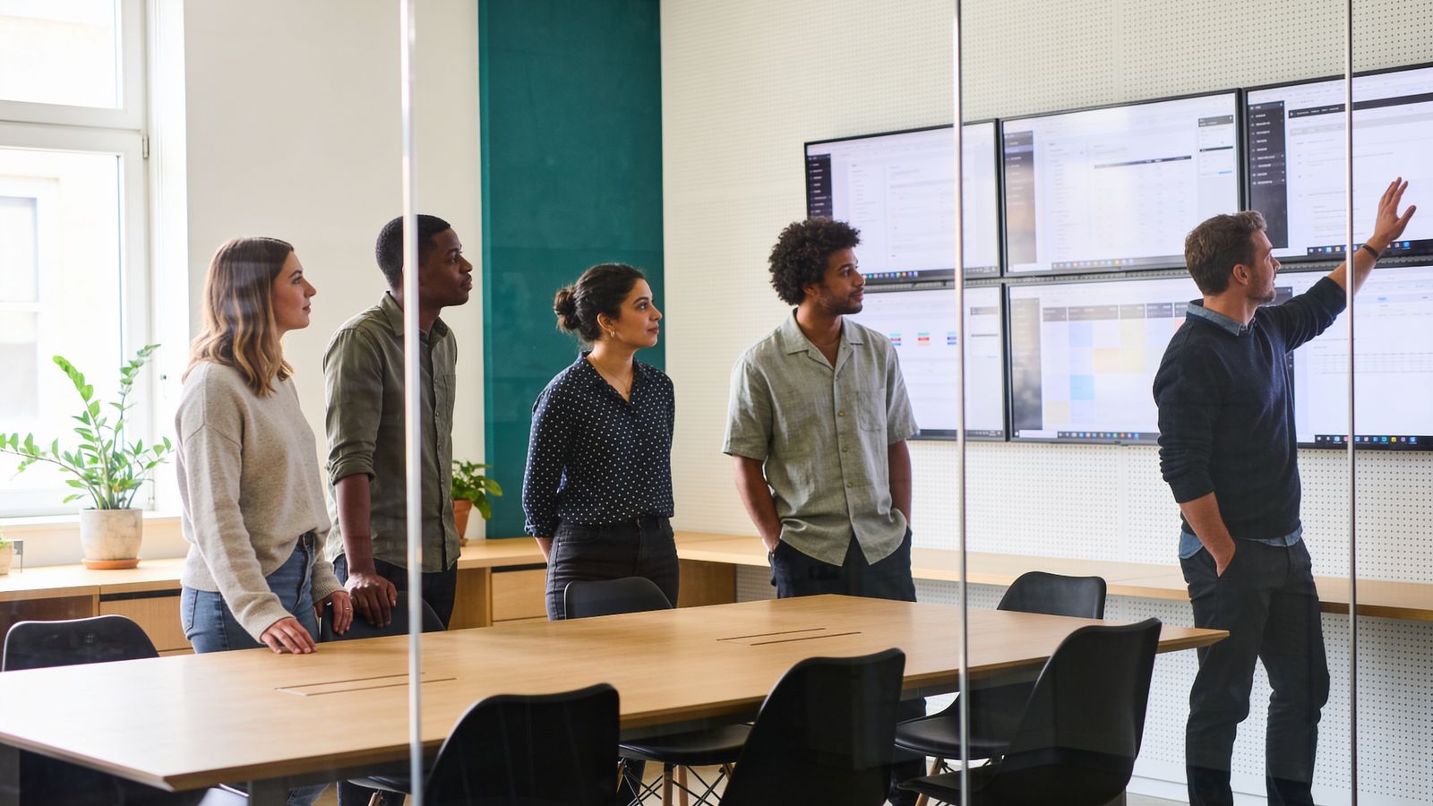 A team stand-up in a glass-walled meeting room